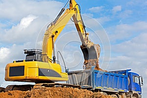 Excavator unloading sand into tipper truck