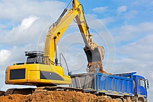 Excavator unloading sand into tipper truck photo