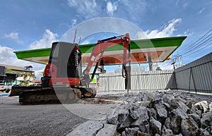 Excavator using hydraulic hammer for breaking concrete at a construction site