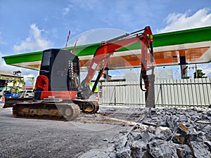 Excavator using hydraulic hammer for breaking concrete at a construction site