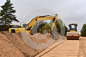 Excavator and Vibro Roller Soil Compactor at road construction and bridge projects in forest area. Heavy machinery for road work.