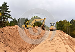 Excavator and Vibro Roller Soil Compactor at road construction and bridge projects in forest area. Heavy machinery for road work.