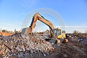 Excavator work at landfill with concrete demolition waste. Salvaging and recycling building and construction materials.