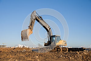 Excavator working at construction site. Backhoe digs ground for the foundation and for paving out sewer line