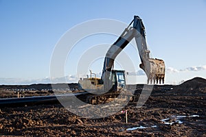 Excavator working at construction site. Backhoe digs ground for the foundation and for paving out sewer line