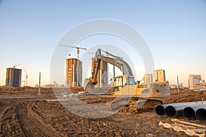 Excavator working at construction site. Backhoe digs ground for the foundation and for paving out sewer line. Construction