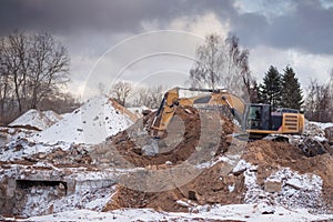 Excavator working at construction site. Backhoe digs ground for the foundation and for paving out sewer line. Construction