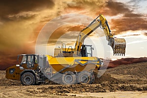 Excavator working on construction site with dramatic clouds on sky