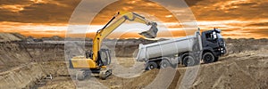 Excavator working on construction site with dramatic clouds on sky