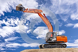 Excavator working on construction site with dramatic clouds on sky