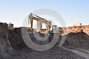 Excavator working at construction site on earthworks. Backhoe digging building foundatio. Construction machinery for excavating,