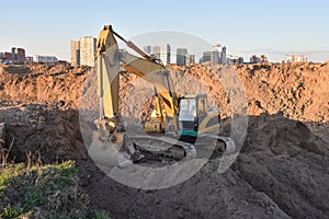 Excavator working at construction site on earthworks. Backhoe digging building foundatio. Construction machinery for excavating,