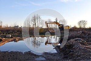 Excavator working at construction site on earthworks. Backhoe digging building foundatio. Construction machinery for excavating,