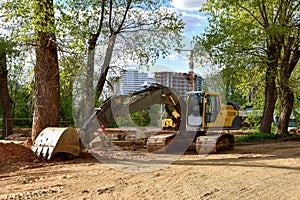 Excavator working at construction site on earthworks. Backhoe digging building foundation and paving out sewer line. Construction