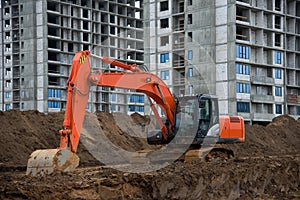 Excavator working at construction site on earthworks. Backhoe digs ground for the foundation and for paving out sewer line.