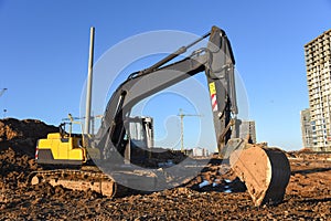 Excavator working at construction site on earthworks. Backhoe on road work digs ground. Paving out sewer line. Construction