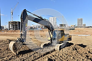 Excavator working at construction site on earthworks. Backhoe on road work digs ground. Paving out sewer line. Construction