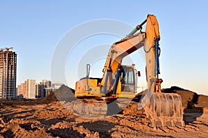 Excavator working at construction site on earthworks. Backhoe on road work digs ground. Paving out sewer line. Construction