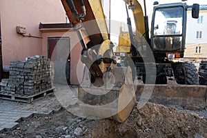 The excavator is working on the construction site to replace the pipeline in winter. Digging holes for laying new pipes for