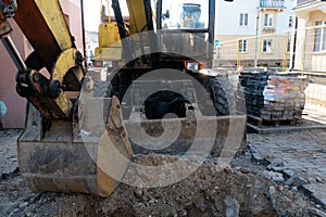 The excavator is working on the construction site to replace the pipeline in winter. Digging holes for laying new pipes for