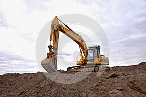 Excavator working on earthmoving at open pit mining on sunset background. Backhoe digs gravel in quarry. Construction machinery