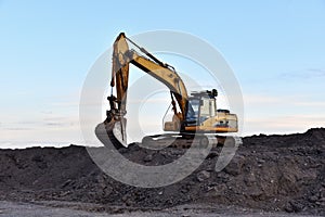 Excavator working on earthmoving at open pit mining on sunset background. Backhoe digs gravel in quarry. Construction machinery