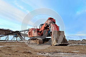 Excavator working in the mining quarry in winter time. Excavator bucket. Large metal iron ladle. Amazing northern sunset on a