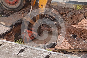 Excavator working on the Repair of pipe water and sewerage on road