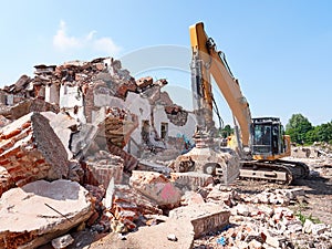 Excavator working in rubble. Old building ruins view.