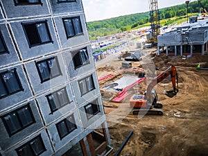 excavator works at a construction site for the construction of new houses from monolithic reinforced concrete