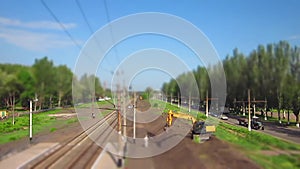 Excavator works near the railroad. Time lapse, tilt-shift. Yellow vehicle bulldozer digging earth