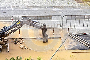 Excavator works to repair a water leak in a asphalt street