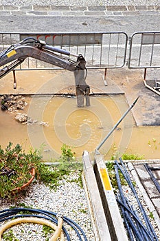 Excavator works to repair a water leak in a asphalt street