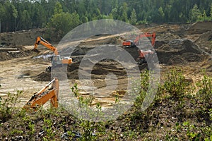 Excavators are developing a sand pit.