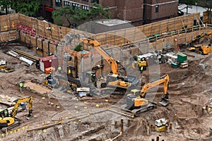 Excavators digging on skyscraper construction site with foundation pit