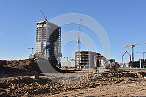 Excavators on earthworks. Backhoe on road work digs ground. Work of tower cranes at construction site Paving out sewer line.