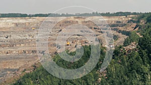 Excavators and heavy trucks in the quarry mining granite TILT-SHIFT