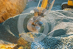 Excavatorsmoving gravel in the construction works of a foundation of the house