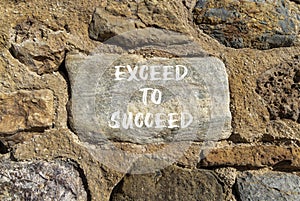 Exceed to succeed symbol. Concept words Exceed to succeed on beautiful big grey stone. Beautiful stone wall background. Business