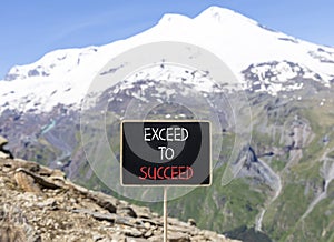 Exceed to succeed symbol. Concept words Exceed to succeed on beautiful black chalk blackboard. Beautiful mountain Elbrus