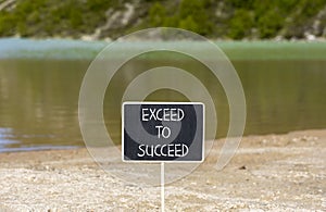 Exceed to succeed symbol. Concept words Exceed to succeed on beautiful black chalk blackboard. Beautiful mountain lake background