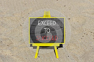 Exceed to succeed symbol. Concept words Exceed to succeed on beautiful black chalk blackboard. Beautiful sand beach background.