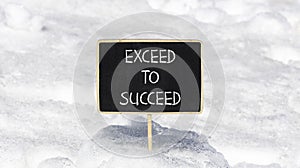Exceed to succeed symbol. Concept words Exceed to succeed on beautiful black chalk blackboard. Beautiful white snow background.