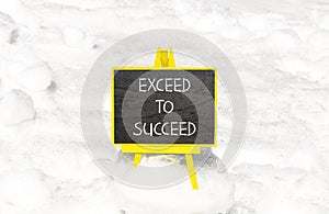 Exceed to succeed symbol. Concept words Exceed to succeed on beautiful black chalk blackboard. Beautiful white snow background.