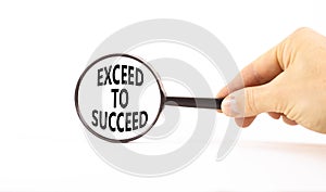 Exceed to succeed symbol. Concept words Exceed to succeed in beautiful magnifying glass. Beautiful white table white background.