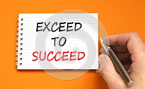 Exceed to succeed symbol. Concept words Exceed to succeed on beautiful white note. Beautiful orange background. Businessman hand.