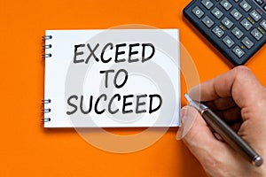 Exceed to succeed symbol. Concept words Exceed to succeed on beautiful white note. Beautiful orange background. Businessman hand.