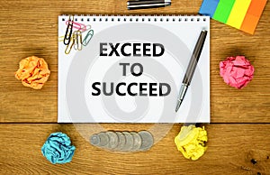 Exceed to succeed symbol. Concept words Exceed to succeed on beautiful white note. Beautiful wooden background. Black pen. Colored