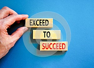 Exceed to succeed symbol. Concept words Exceed to succeed on beautiful wooden blocks. Beautiful blue table blue background.