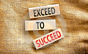 Exceed to succeed symbol. Concept words Exceed to succeed on beautiful wooden blocks. Beautiful canvas table canvas background.